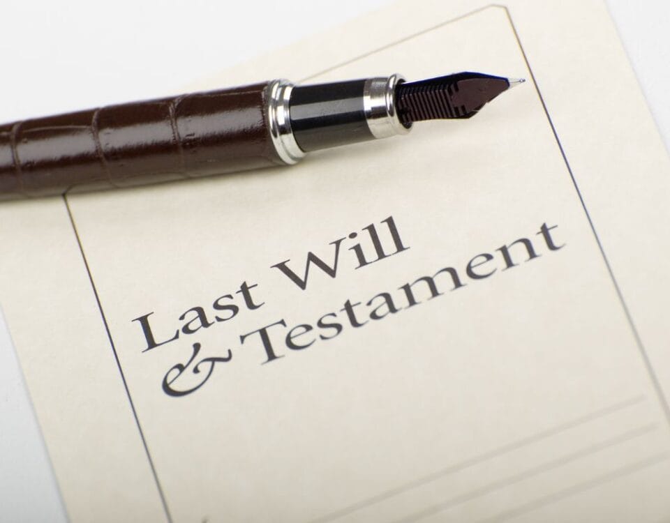 A photo of a piece of paper that says Last Will And Testament. There is also a pen above the text.